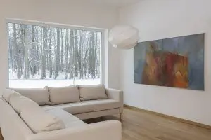 Bright living room with freshly painted white walls and winter scenery outside, showing winter is a good time for interior painting in a comfortable, well-lit home interior