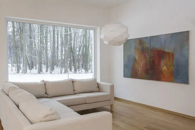Bright living room with freshly painted white walls and winter scenery outside, showing winter is a good time for interior painting in a comfortable, well-lit home interior