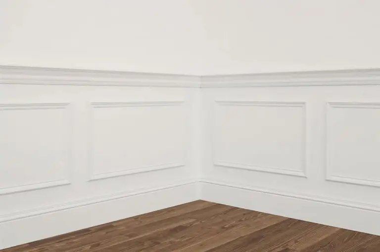 Freshly painted white interior trim and wall paneling in a finished room, showing clean lines and smooth results when you can you paint interior trim in cold weather conditions.