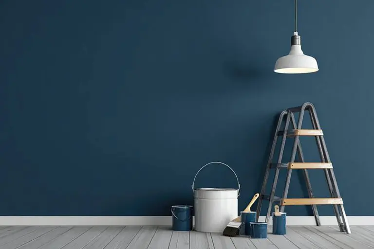 Best paint finishes for interior walls in Troy homes shown on a freshly painted blue interior wall with painting tools and ladder.