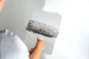 A painter rolling gray paint onto an interior wall — what to ask before hiring a painter in Northville