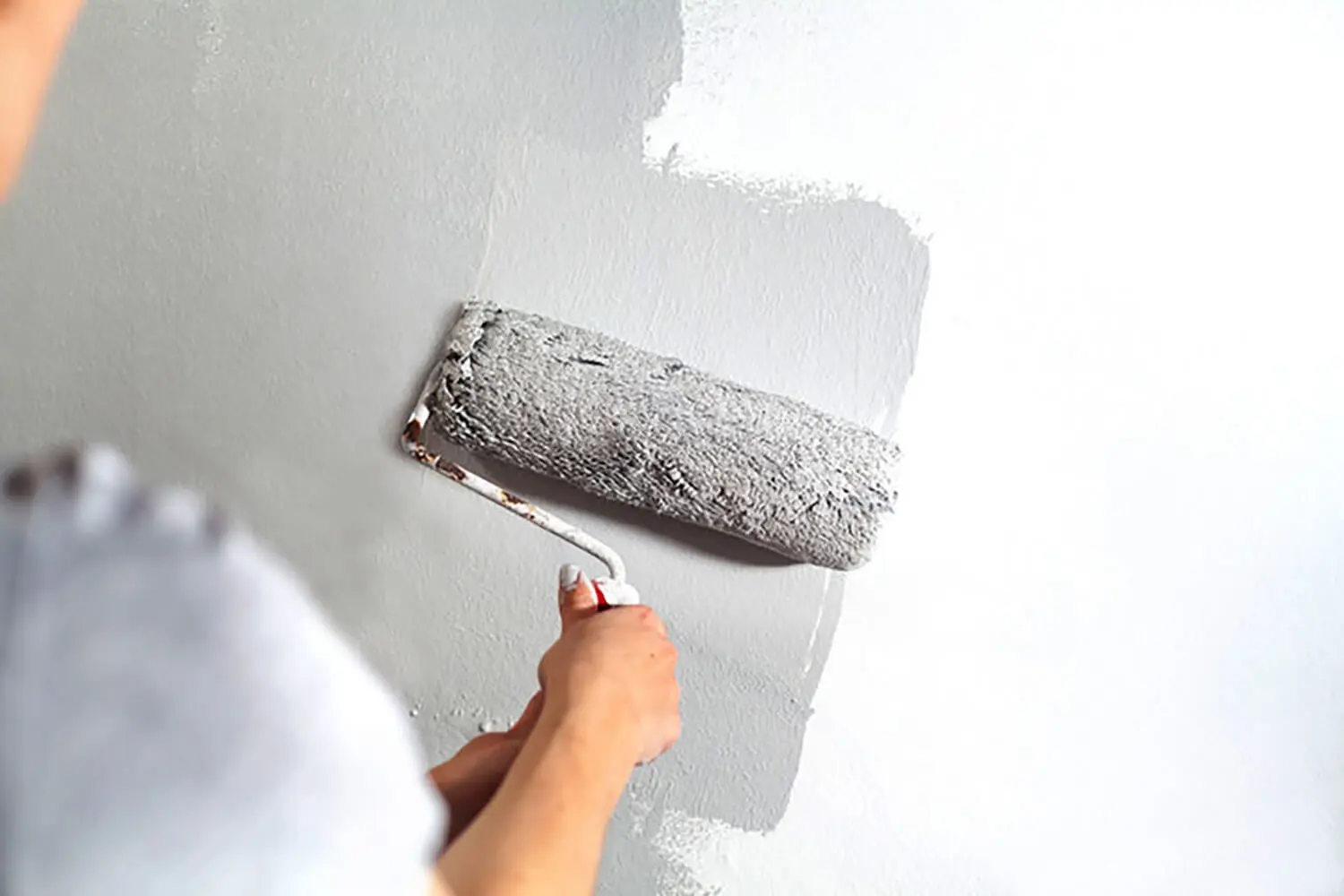 A painter rolling gray paint onto an interior wall — what to ask before hiring a painter in Northville