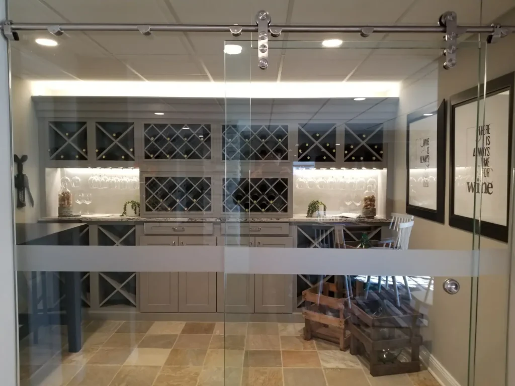 Contemporary glass wine room with custom metal framing, integrated storage and polished interior finishes in a Metro Detroit residence.