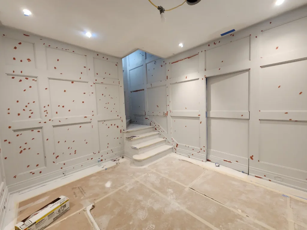 Interior wall paneling and trim during surface preparation, with numerous repair spots marked before refinishing.