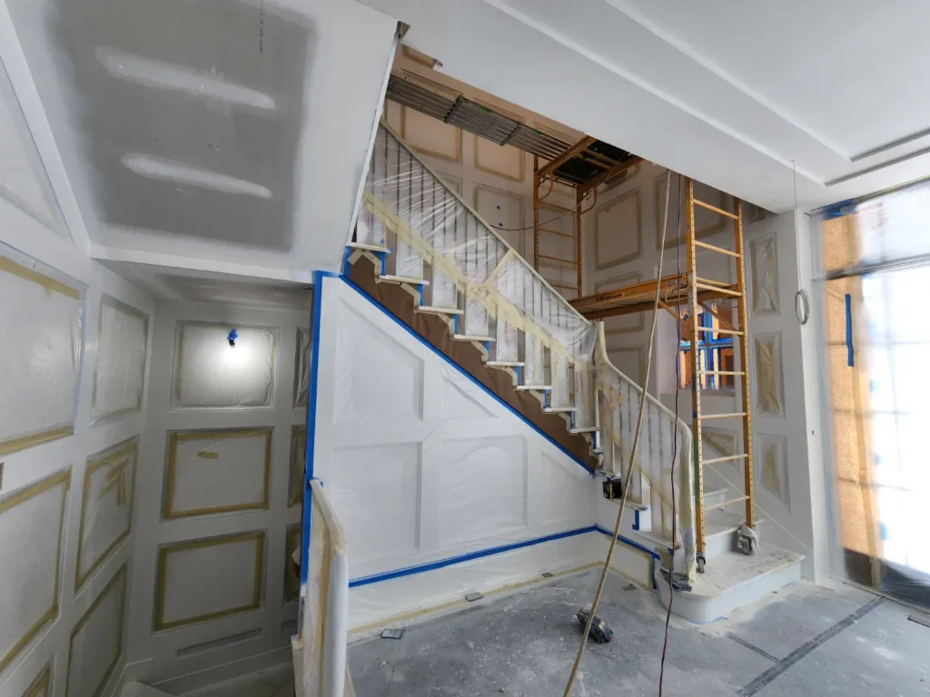 Interior staircase and paneled walls masked and protected during preparation for a high-gloss lacquer finish.