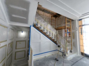 Interior staircase and paneled walls masked and protected during preparation for a high-gloss lacquer finish.