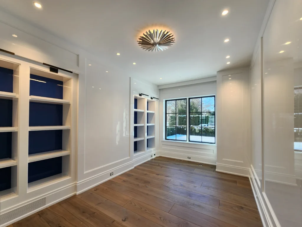 Custom built-ins with white high gloss shelving and deep blue high-gloss back panels and a sunburst light fixture on the ceiling