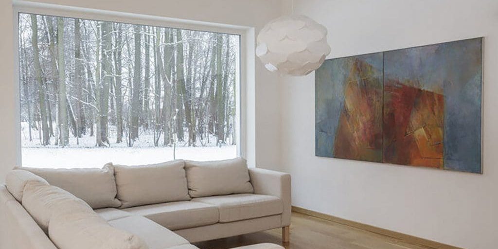 Bright living room with freshly painted white walls and winter scenery outside, showing winter is a good time for interior painting in a comfortable, well-lit home interior