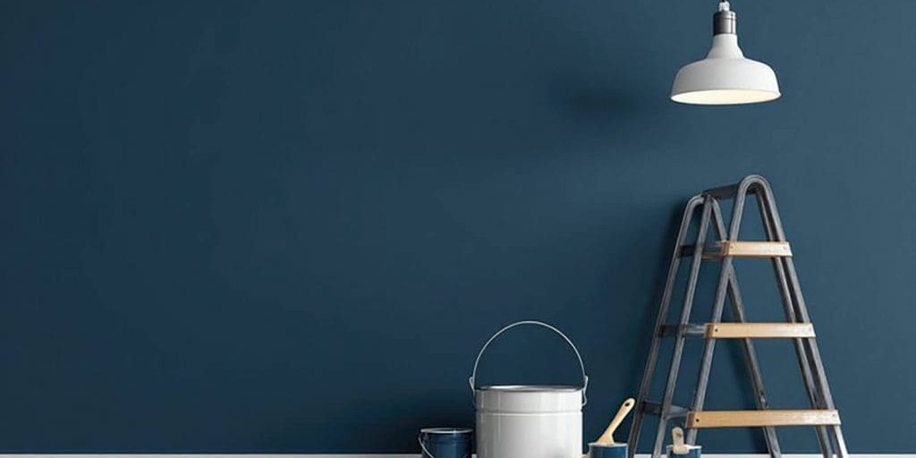 Best paint finishes for interior walls in Troy homes shown on a freshly painted blue interior wall with painting tools and ladder.