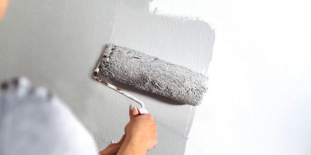A painter rolling gray paint onto an interior wall — what to ask before hiring a painter in Northville